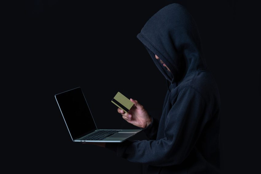 The concept of cyber theft. Hackers holding gold smart cards and white notebooks on a black background